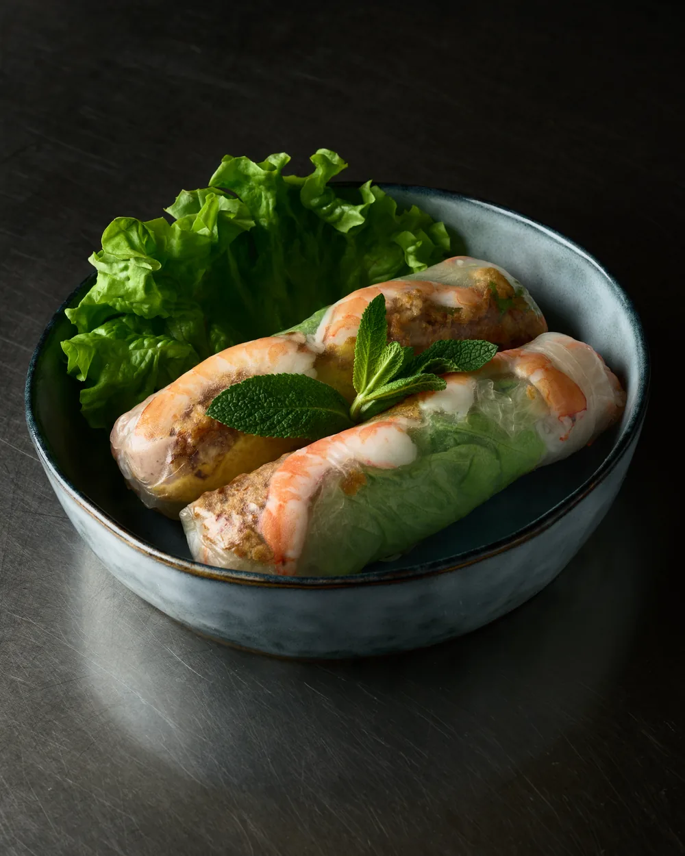 Rouleaux de printemps aux crevettes et à la menthe, dans un bol en grès sur fond ardoise