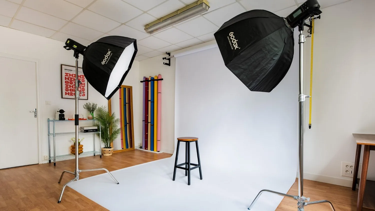 Studio photo du studio Klyp : colorama blanc déroulé, deux boîtes à lumière sur pied et rouleaux de fonds papier couleur