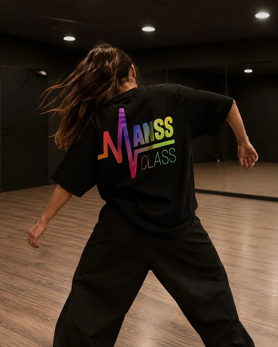 Danseuse de dos portant un t-shirt noir floqué du logo Manss Class en dégradé arc-en-ciel