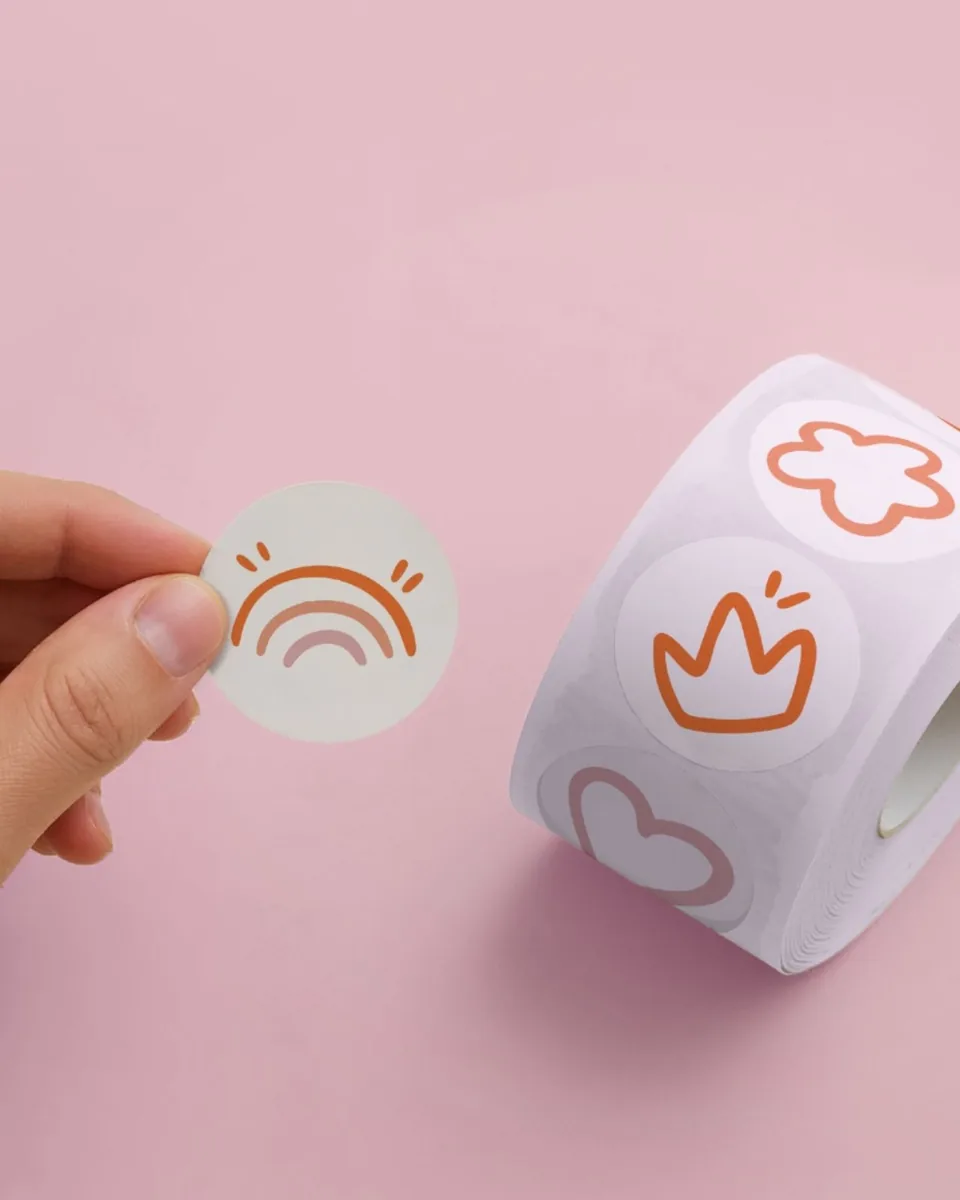 Rouleau de stickers ronds Story’Croch sur fond rose, avec les motifs arc-en-ciel, couronne et fleur