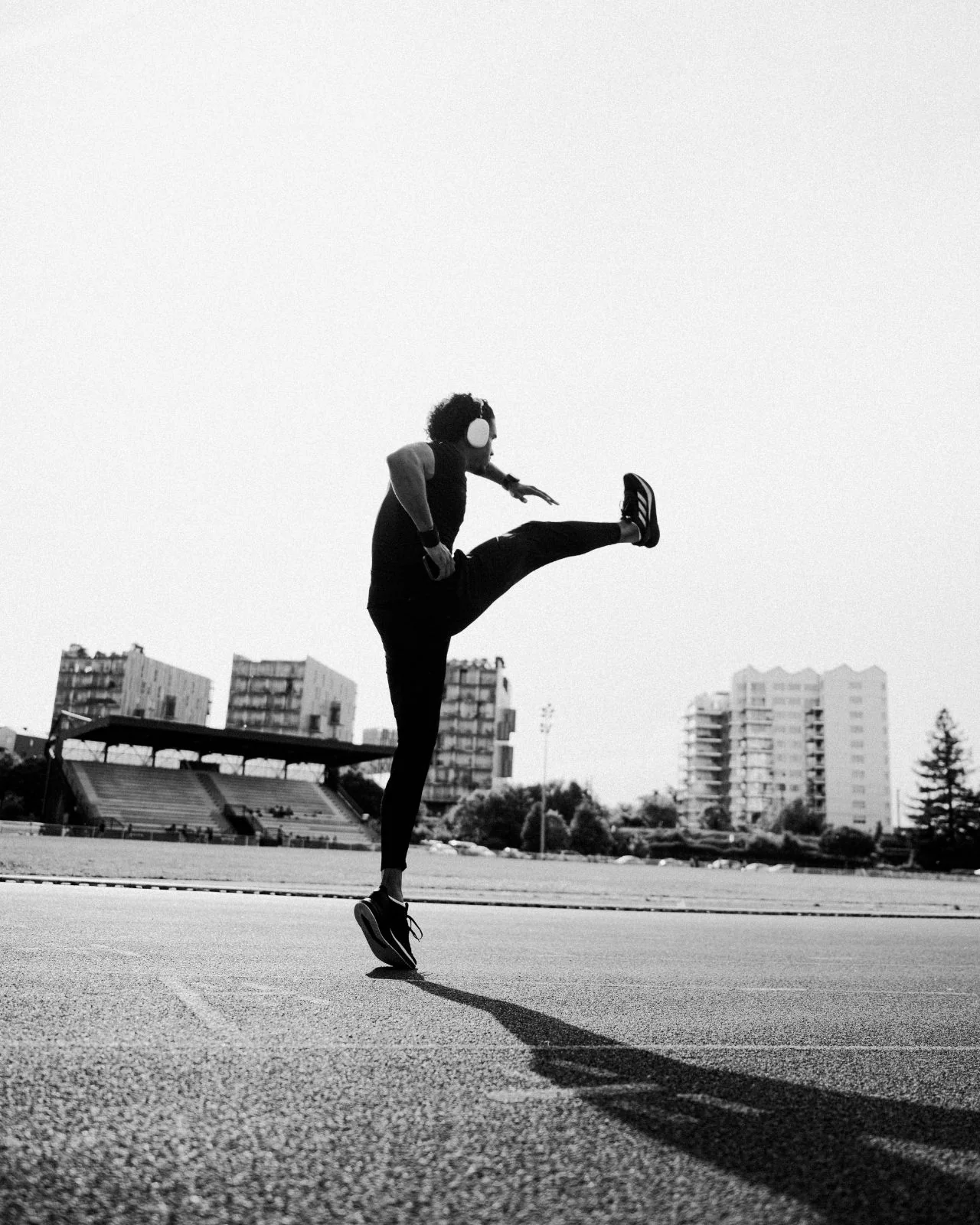 Athlète en plein étirement sur une piste d’athlétisme, à contre-jour