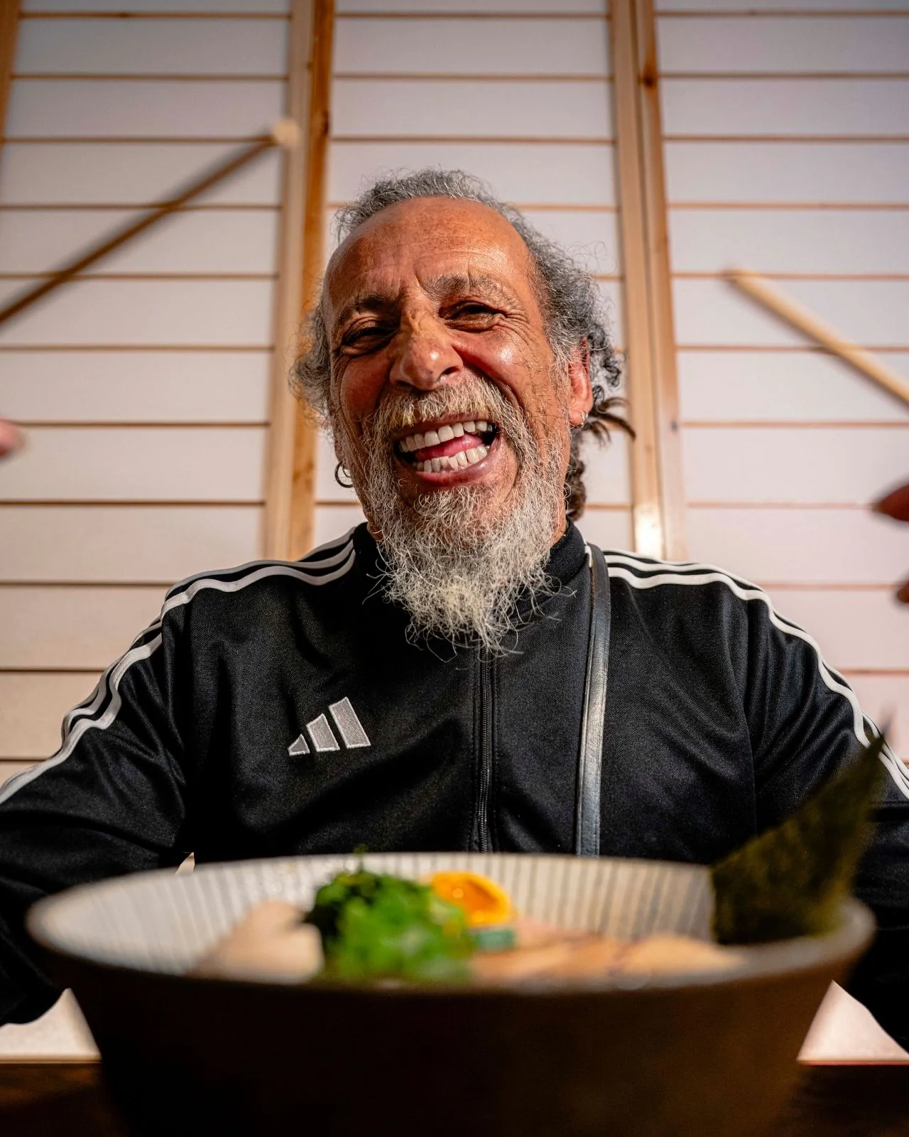 Portrait souriant d’un restaurateur derrière un bol de ramen