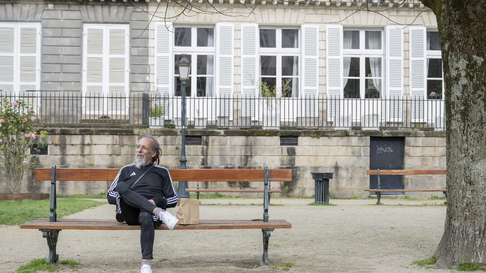 Le personnage du spot Ikimasho assis seul sur un banc, place arborée à Nantes