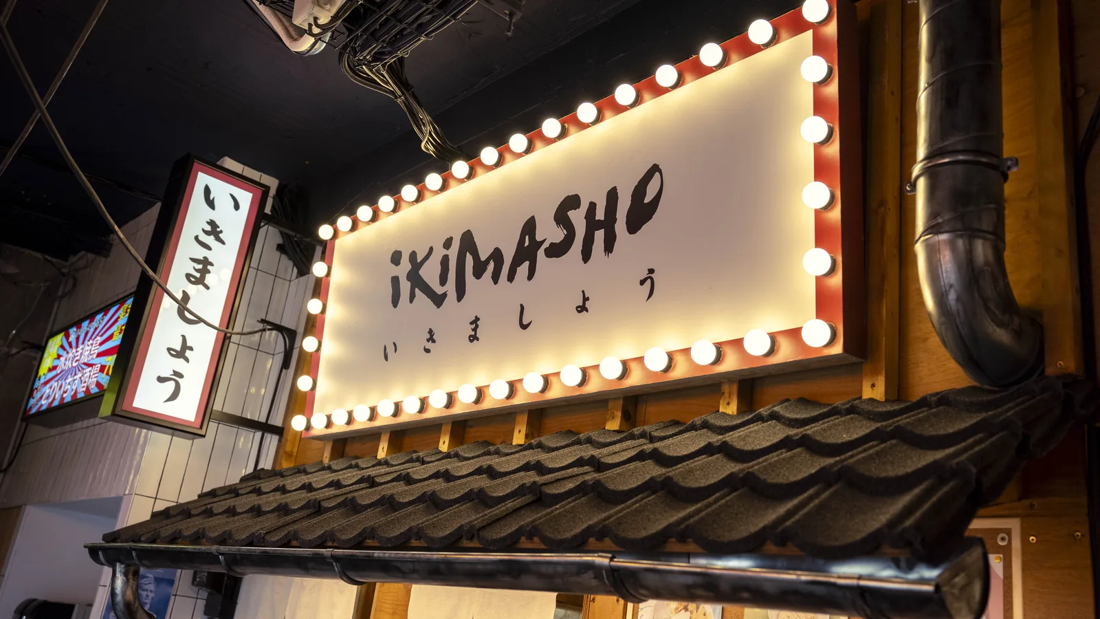 L’enseigne lumineuse du restaurant Ikimasho, lettres blanches sur bandeau à ampoules