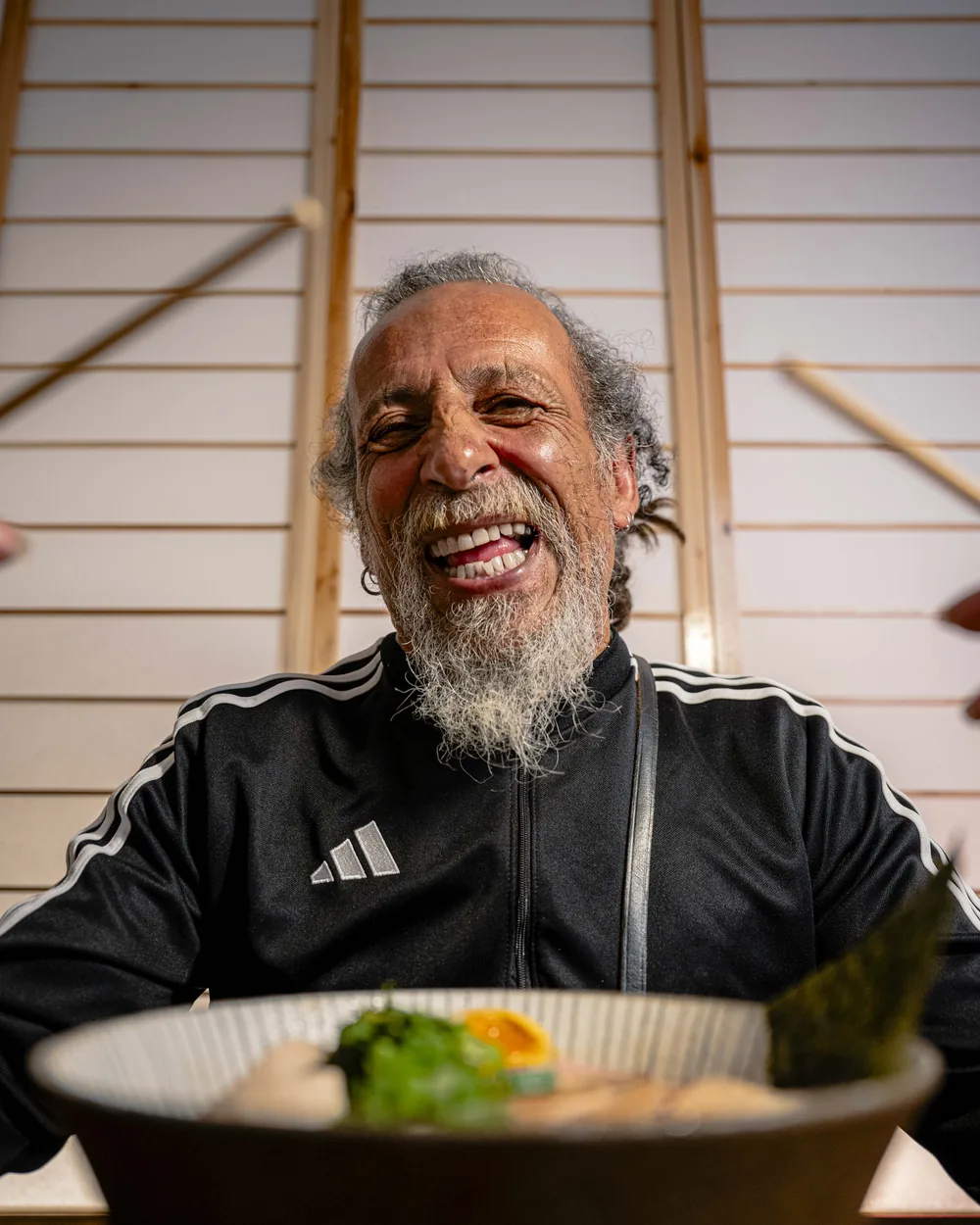 Portrait souriant du personnage du spot Ikimasho, attablé devant un bol