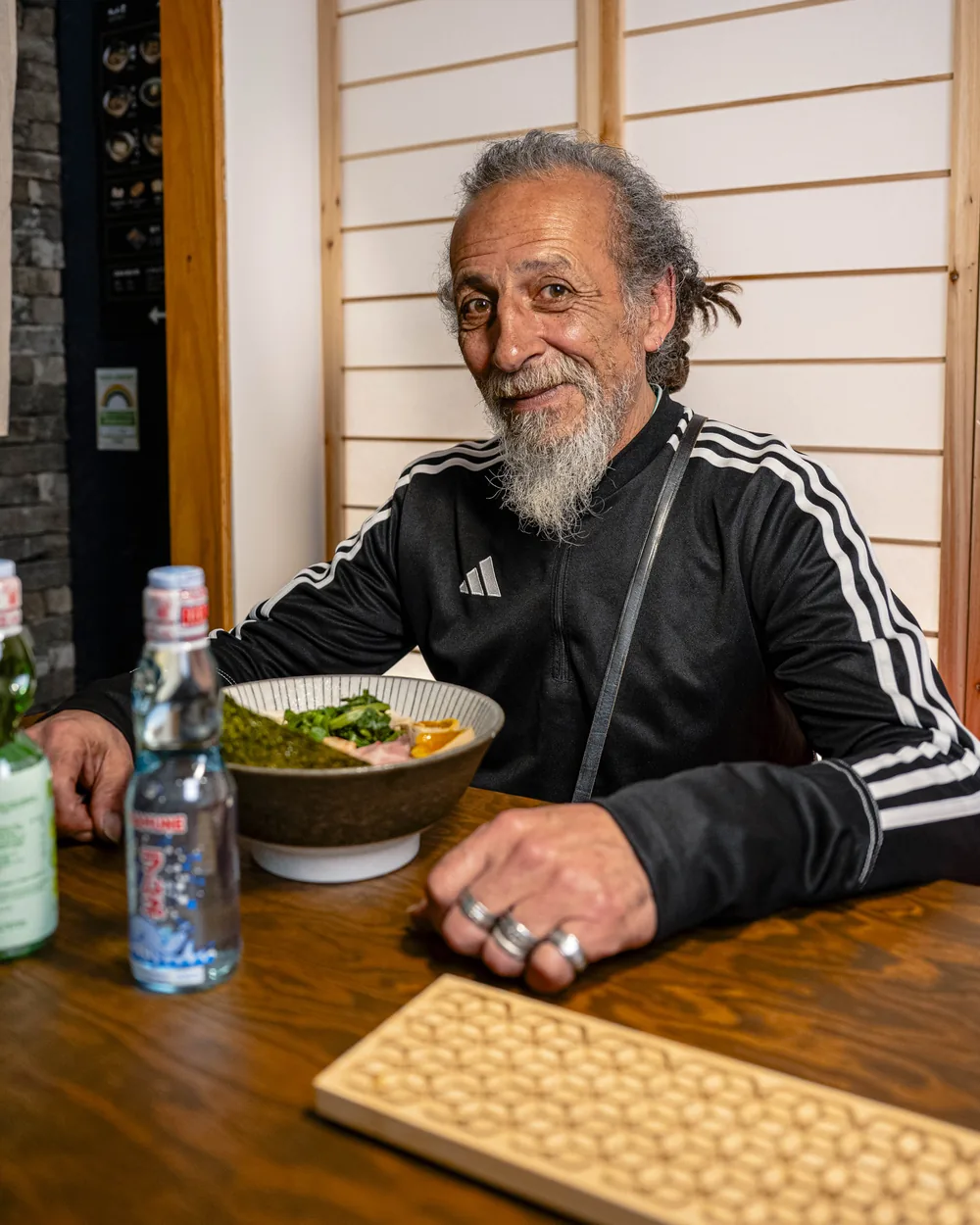 Le personnage du spot Ikimasho attablé en terrasse, bol et boissons devant lui