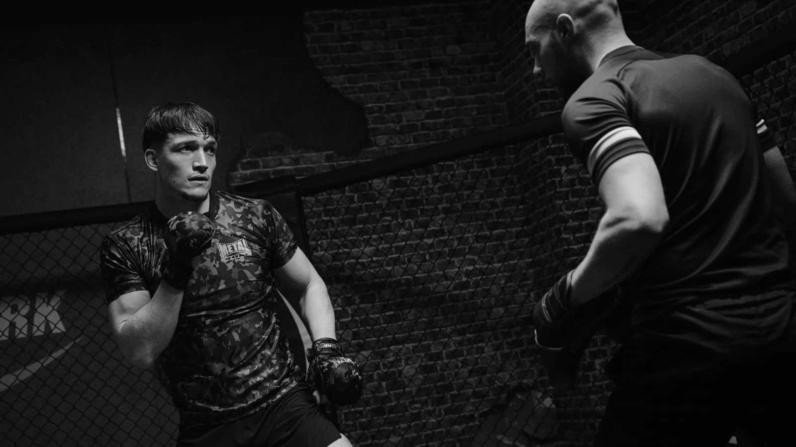 Deux combattants face à face dans une cage, en noir et blanc