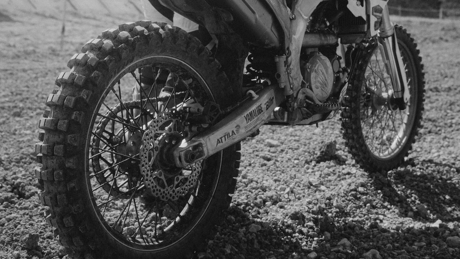 Gros plan sur la roue avant crantée d’une moto de cross, en noir et blanc