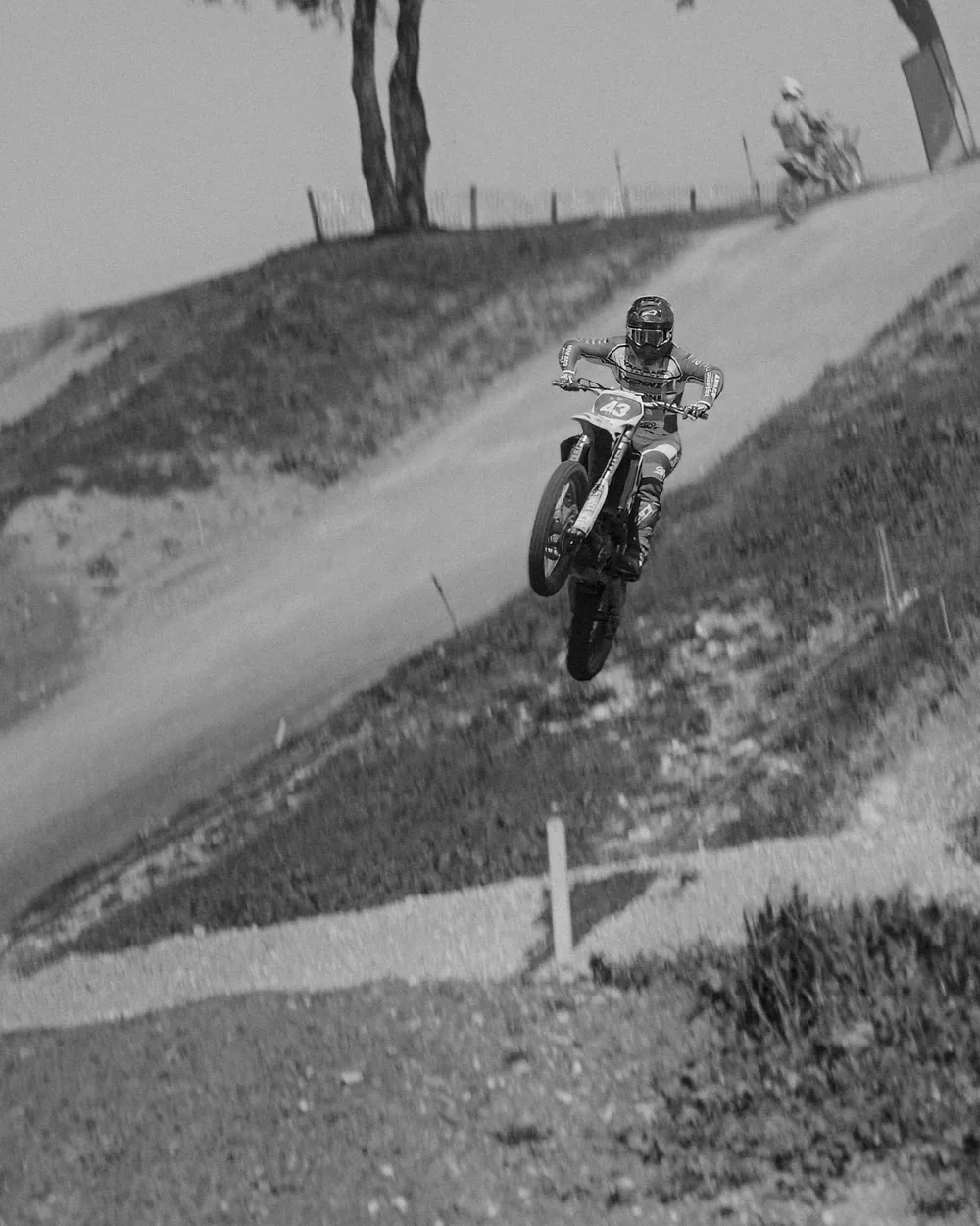 Pilote de motocross en plein saut au-dessus d’une bosse, en noir et blanc